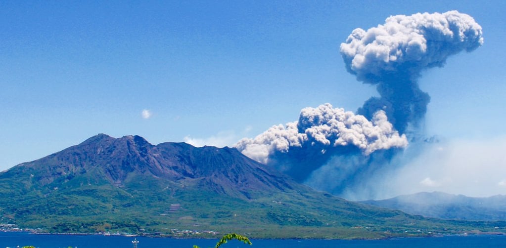 sakaurajima erupting in Japan in a blue sky with plumes of smoke