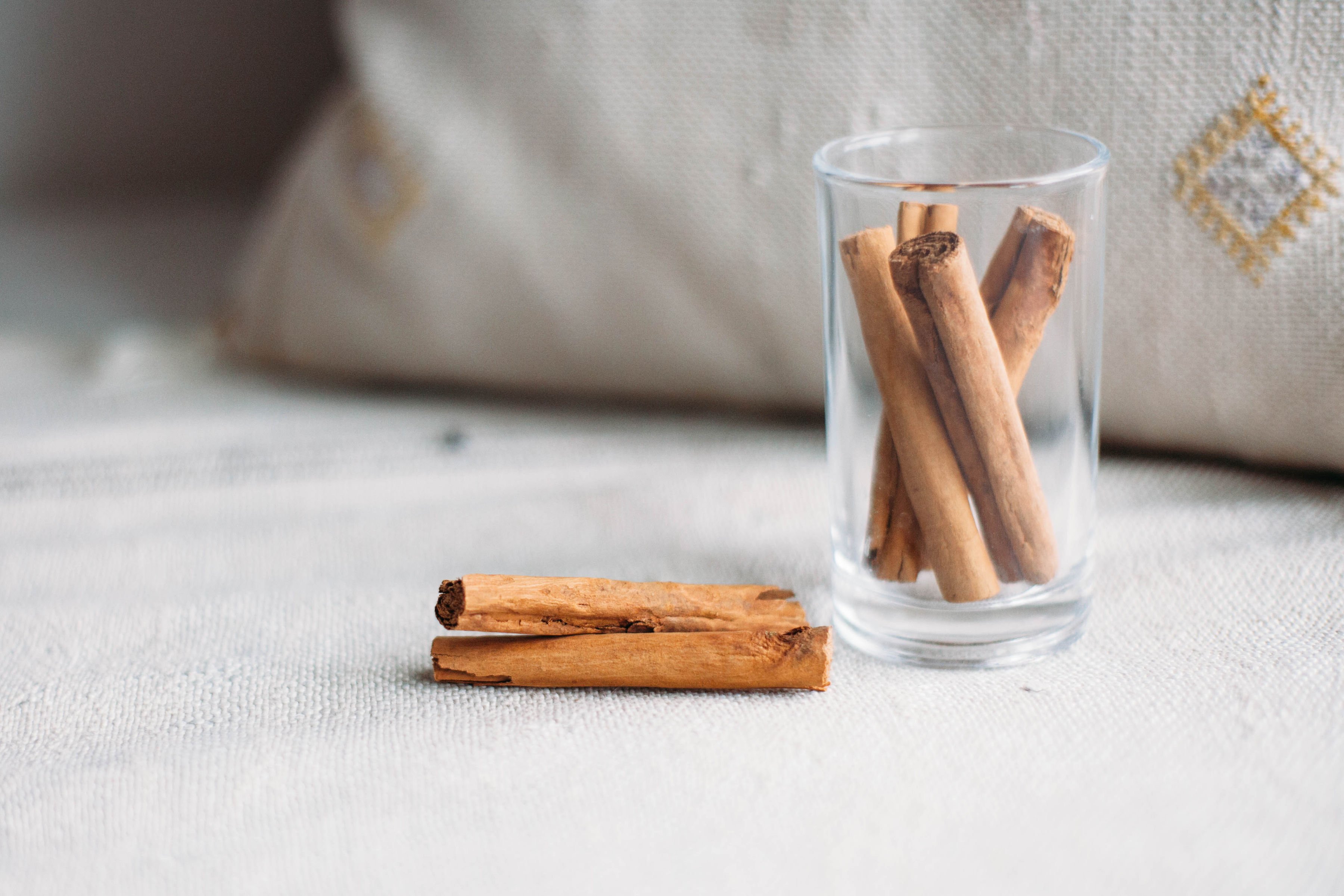 cinnamon sticks laying on a cloth and in a clear glass