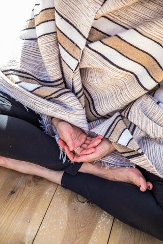 Woman sitting with a blanket wrapped around her and her hands in her lap