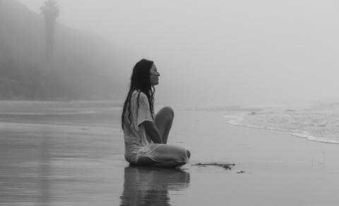 Woman sitting on the beach in the rain