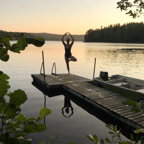 Woman doing yoga on the dock of a lake at sunset
